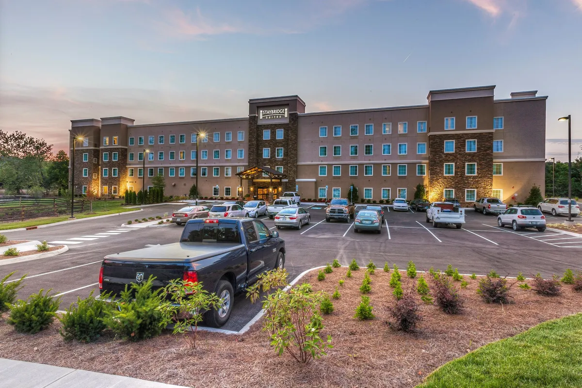 A wide-angle view of the hotel’s main entrance, featuring the prominent entrance canopy and visible parking area. The facade is welcoming, suggesting easy access for guests and a hospitable arrival experience.