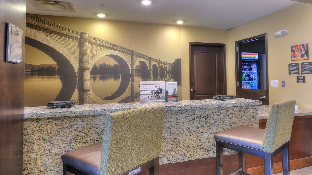 A welcoming interior with a granite reception desk, mural art, and a comfortable seating area. The space invites guests to relax, make inquiries, and enjoy attentive personalized service.